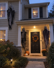 Three hanging Skeleton Trio figures decorating a front porch at dusk